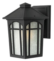 Black Hinkley wall lantern with a pyramidal roof, arched window mullions and pale textured panels.