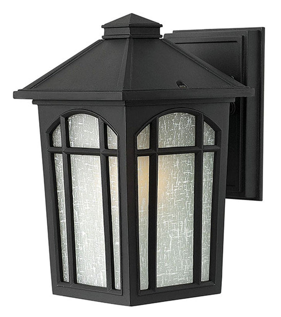 Black Hinkley wall lantern with a pyramidal roof, arched window mullions and pale textured panels.