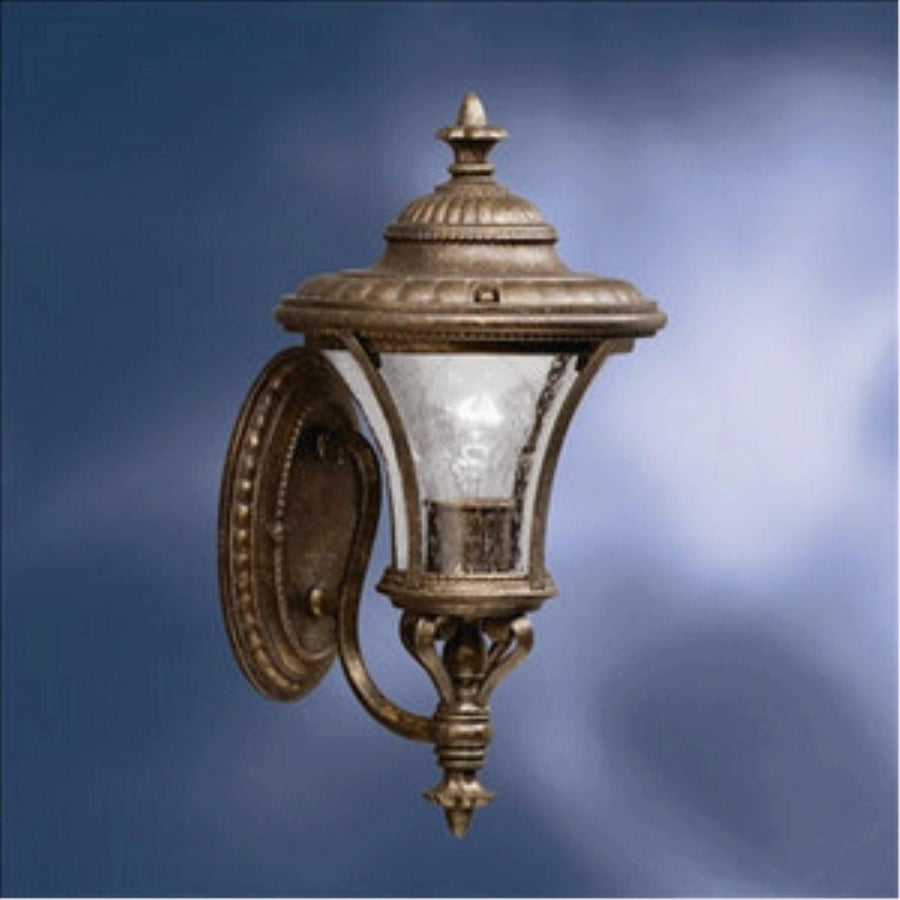 Kichler 9394TZG outdoor wall lantern with a bronze-and-gold frame, clear textured glass and ornate finials
