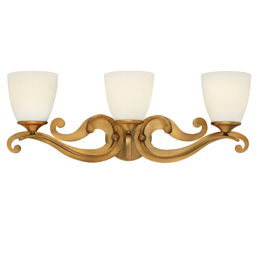 Hinkley Reese brushed-bronze vanity light with three pale cup shades and ornate scrolling arms.