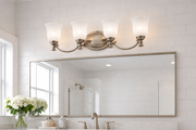 Francoise vanity light with four upward fluted shades above a bathroom mirror