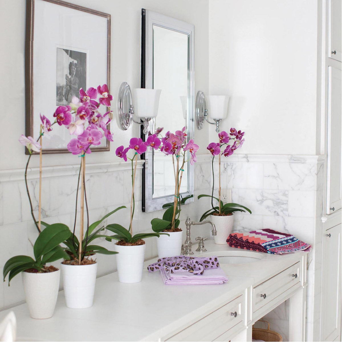 Hinkley Shelly wall sconces in a wider bathroom view with mirrors and foreground flowers