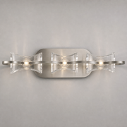 Mantra Krom wall light with three clear curved panels and a satin nickel wave-shaped band.