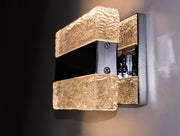 Angled view of the Maxim Ice wall light illuminated against a dark wall.