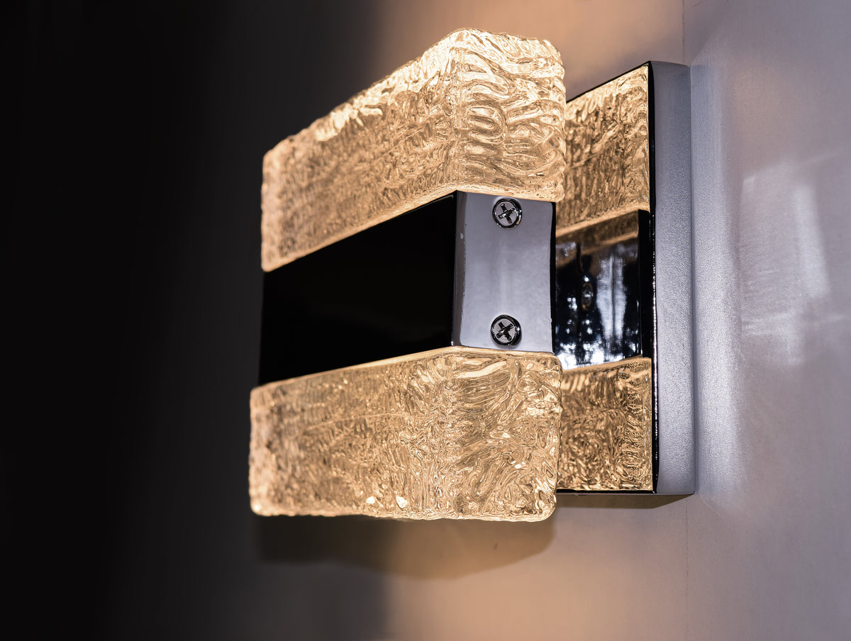 Angled view of the Maxim Ice wall light illuminated against a dark wall.
