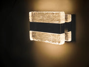 Front view of the Maxim Ice wall light with illuminated upper and lower textured blocks against a dark wall.