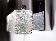 Close-up of a textured clear block corner, retaining edge and screw on the Maxim Ice wall light.