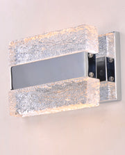 Front-angle view of textured clear blocks, side screws and reflective backplate on the Maxim Ice wall light.