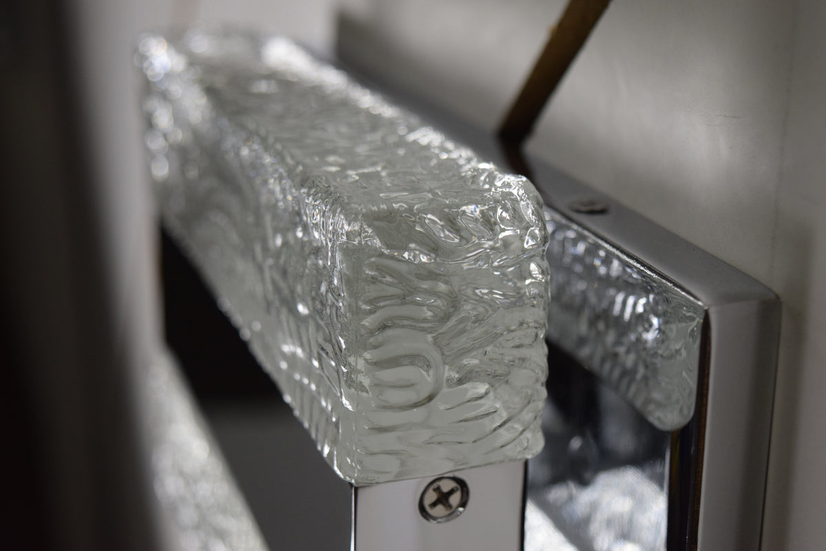 Close-up of clear relief texture, adjoining reflective metal and backplate on the Maxim Ice wall light.